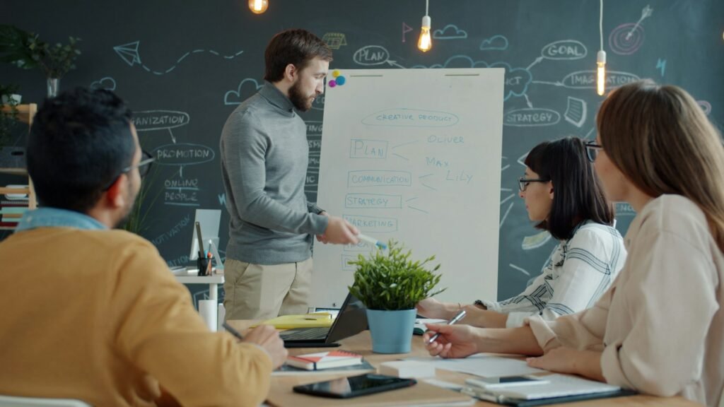 Team collaborating around a whiteboard mapping out a process in a modern office